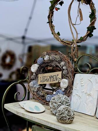 Stand auf der Handwerkerstraße mit einem Blumenkranz und Wilkommensschild 