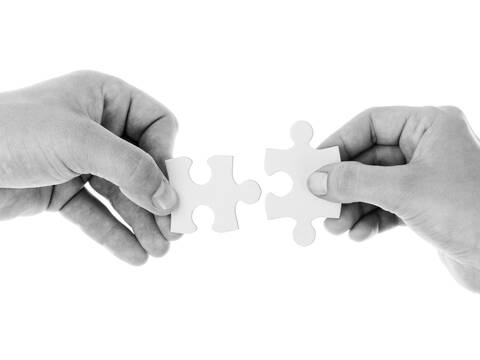 Hände setzen Puzzleteile zusammen als Symbol für das Ineinandergreifen guter Ideen