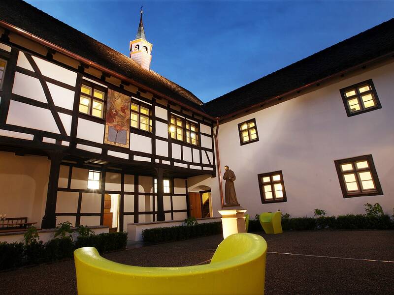 Innenhof des Kapuzinerklosters bei Nacht mit Fachwerkfassaden und Türmchen im Hintergrund