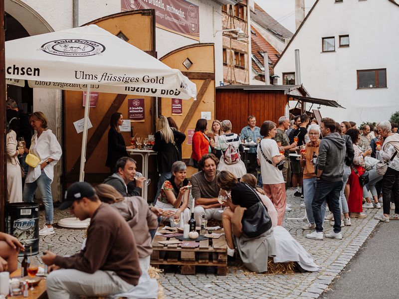 Menschen genießen vor der künftigen Genussmanufaktur ein After-Work-Event