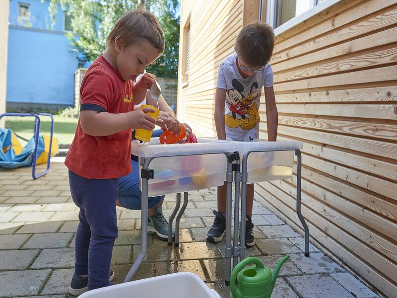 Spielende Kinder an einem Wasserspielgerät des Kindergartens Eichenau mit Schulkindergarten