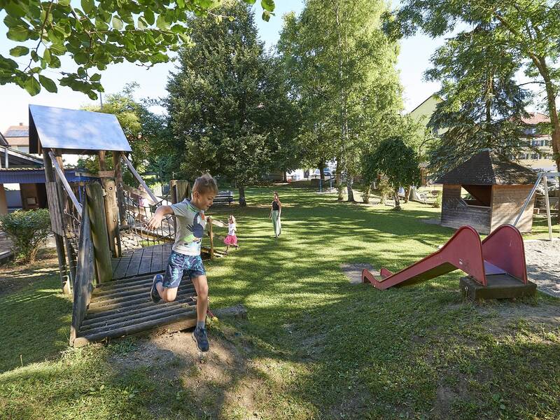 Spielendes Kind inmitten der Spielgeräte im begrünten Außenbereich des Kindergartens Grüningen