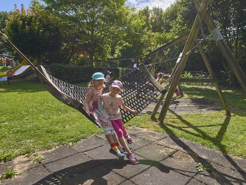 Zwei Kinder spielen in Hängematten auf dem Gelände der Kindertageseinrichtung Regenbogen