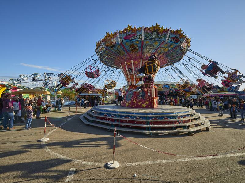 Ein belebtes Volksfest (Gallusmarkt) mit einem sich drehenden Kettenkarussell und vielen Besuchern bei Tageslicht.